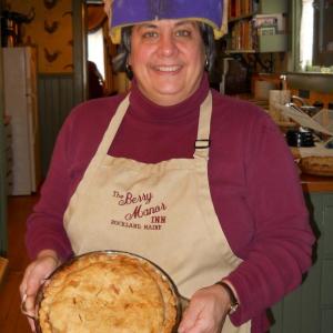 Cheryl Michaelsen, of Berry Manor Inn, holds one of the 50 or so pies baked while wearing her once-a-year pie slice hat. (Photo courtesy of Historic Inns of Rockland).