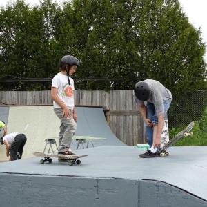 Nine-year-old Finn Cotrell (left foreground) and John Seekins (far right) stand atop one of the ramps in the skatepark. (photo by Erica Thoms)