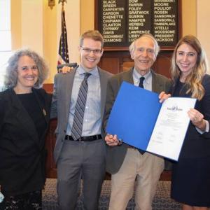 Senator Herbig, far right, presents Bill Carpenter, second from right, with a legislative sentiment in the Senate Chamber. Donna Gold, left, and Ursa Beckford (College of the Atlantic graduate and Senator Herbig’s aide) also attended. (Photo courtesy Senator Herbig’s office)