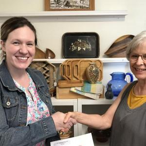 Becca Gildred, KCHC development director (left) accepts a check from Elaine Bisbee, Heavenly Threads staff member and volunteer. (Photo courtesy Knox County Homeless Coalition)