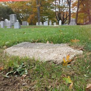 Walter Guptill pondered over this old concrete foundation for the Bennett stone that remains on the Bennett family lot. According to records, the gravestone read: “E. Bennett and Family.” There was no other information on the stone. (Photo by Walter Guptill)