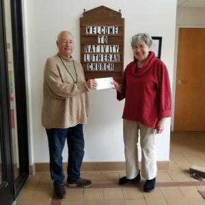 Jeanne Denney (right), accepts a check for $2,000 on behalf of the Community Emergency Shelter Pilot Committee from Karin Pratt of Nativity Lutheran Church, Rockport