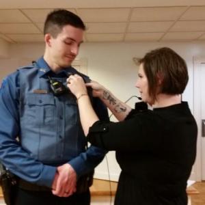 Jonathan Poole’s wife, Ashley, pins his badge on his police uniform during a pinning ceremony at the Rockport Select Board meeting Dec. 9. (Photo by Sarah Shepherd)
