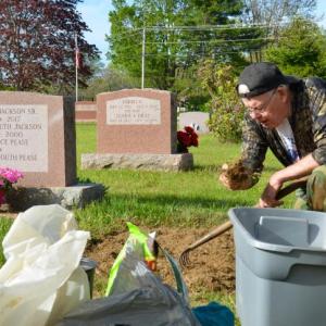 Bernard Jackson, Jr., tends to the lot in the graveyard where his parents lie, in the Rockville neighborhood of Rockport, on Memorial Day. He drove down from Liberty to take care of the family graves. “It is about respect,” he said, succinctly. (Photo by Lynda Clancy)