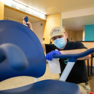 Starr Sarabia, a Patient Services Support Tech at Maine Medical Center, sanitizes a wheelchair. (Photo courtesy MaineHealth)