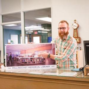 Matt DeLaney, director of the Millinocket Memorial Library, with a rendering of renovations planned for the library. (Photo by Thalassa Raasch/Maine Community Foundation)