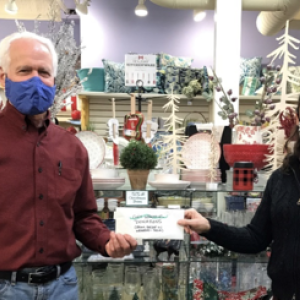 John Viehman, Executive Director of United Midcoast Charities, receives a check from Sierra Dietz, Owner of the Grasshopper Shop of Rockland.