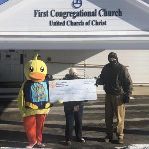 Left and right, Lucky the Duck and West Bay Rotarian Leamon Scott, present a check to Shields Mission Project Administrator Jeanne Denny (center)
