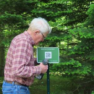 Steve Hardy installing one of the new QR code signs, this one at Norton Cemetery. Who knows where that is? Hint: some call it the Old Settlers’ Cemetery.
photo by Jane Hardy Steve Hardy