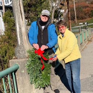 Doug Cole and Martha Bouchard hang wreaths on the bridge on Pascal Ave overlooking the harbor. (Photo courtesy Rockport Garden Club)