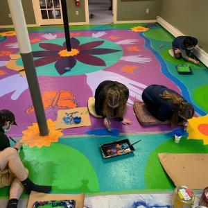 Arts in Action youth artists creating a vibrant floor mural for Coastal Recovery Community Center at St. Peter’s in Rockland. (Photo courtesy RSU13 Adult and Community Education)