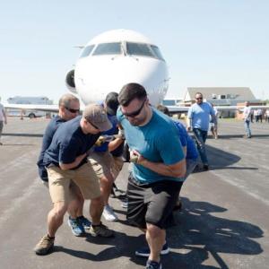 Auburn police officers Travis Barnies, right, and Derek Drouin, second from left, anchor the Auburn Policy Department team at last year’s Big Brothers Big Sisters of Mid-Maine Plane Pull to support local youth mentoring. (Photo by Daryn Slover/Sun Journal)