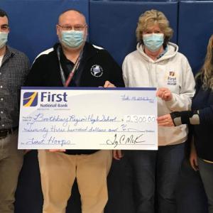 Boothbay Region High School Athletic Director Allan Crocker, second from left, and girls varsity basketball coach Bruce Orne, left, accept a First Hoop donation from Brenda Blackman, third from left, and Shannon Wenners, both of First National Bank. Courtesy photo