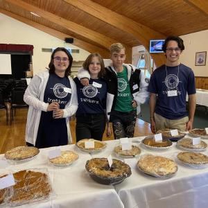 Trekkers students Ada Hansen, Skyler Worley and Curtis Hall with AmeriCorps Member, Ryker Weaver, arranging pies for the Pie Sale table at the Community Auction.