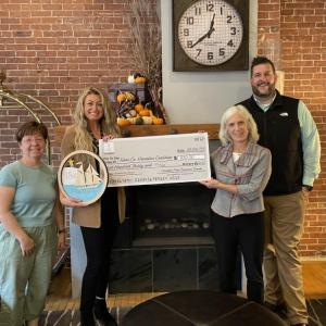 (L to R) Amy Rollins, Jody Landrith, and Erick Anderson, volunteers for Christmas By the Sea, present a check in the amount of $930 to Stephanie Smith (second from right) of the Knox County Homeless Coalition Board of Directors. The donation was made possible by Christmas By the Sea ornament sales last December. (Photo courtesy Camden Area Business Group)