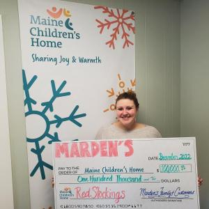Maine Children's Home Christmas Program Director Amanda Simmons holds a giant check of $100,000 from the Marden family and customers of Marden's Surplus & Salvage. (Photo courtesy Maine Children's Home)