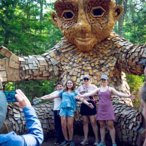 Visitors pose for pictures in front of one of the trolls installed by artist Thomas Dambo at Coastal Maine Botanical Gardens. The trolls have taken permanent residence and are now part of a worldwide scavenger hunt. Courtesy of CMBG