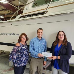 Jason Constantine, president of Back Cove Yachts, presents a check for Rockland Rotary's Inclusive Playground Project to club president, Tena Wallace (L) and Rotarian Susan Page (R) for $2,500.