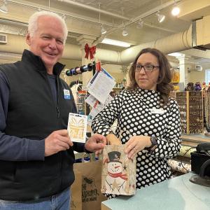 UMC President John Viehman, along with Sierra Dietz, owner of The Grasshopper Shops, draw the winning ticket for UMC's Day of Giving raffle. (Photo courtesy United Midcoast Charities)