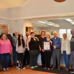 Linda Greenlaw, at the Rockport Town Office May 10, receives recognition as recipient of the annual town report dedication. She is surrounded by family and Rockport Select Board members. (Photo by Lynda Clancy)