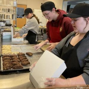 L - R: Culinary Arts students Teagan Fournier, Dakota Smith, and Bella Greene, all Belfast Area High School seniors, package their handmade scones for Hospice Volunteers of Waldo County. (Photo courtesy Waldo County Technical Center)