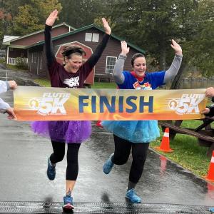 Christine Cleary from Waterville (left) and Deborah Reinmann from Dover, Massachusetts (right) cross the finish line together at the 2023 Flutie 5K at Pine Tree Camp.