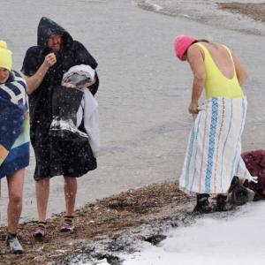 Snow Moon Selkies’ 9 a.m. dip at Naskeag Point in Brooklin was the height of Sunday’s storm. Sarah Havener on the left by Monday had raised $1,600 for Finding Our Voices. (Photo by Michael Percy)