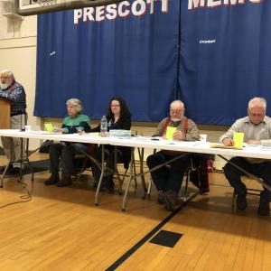 three men and two women sit at a table officiating a meeting