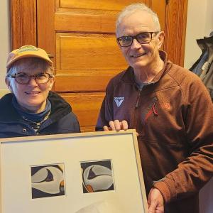 Rotarian Peter Lindquist (right) presents a dyptych pastel by the late Paul Plante to lucky winner Ali Dailey.