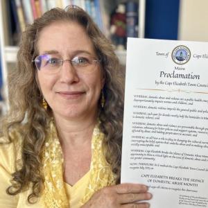 Rachel Davis, director of the Thomas Memorial Public Library, with the town of Cape Elizabeth proclamation declaring that "Domestic abuse is a public health emergency disproportionately impacting women and children" and deeming the Finding Our Voices and library July collaboration "an opportunity to shine a critical light on the domestic abuse in our greater community." (Photo by Patrisha McLean)