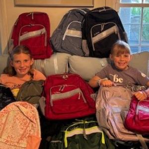 Two future Rotarians are all smiles as they help unload this year’s donation of 90 backpacks from L.L. Bean. (Photo courtesy West Bay Rotary)