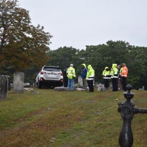 Car in cemetery as seen from driveway gate