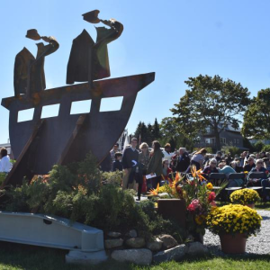 Saturday, Sept. 24, 2022, a large crowd gathers for a ceremony commemorating crew of El Faro and dedicating a sculpture in their honor. Another ceremony will be held Sept. 27, 2025 to recognize the tenth anniversary of the vessel's sinking. (Photo by Sarah Thompson) View of a memorial sculpture with ceremony attendees in the background.