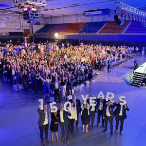 People in foreground each raise the numbers and letters of "150 YEARS"