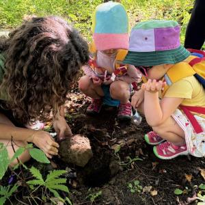 (Photo courtesy Georges River Land Trust) Woman and two toddlers squat down to peer into a hole