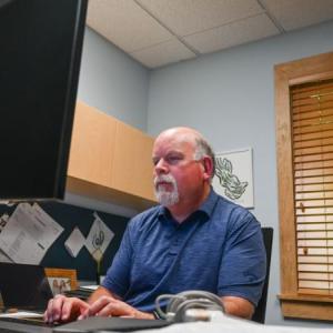 Mike Arsenault sits at his desk.