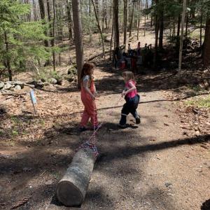 Two girls drag a log using rope