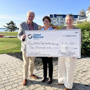 Man and two women pose while holding an oversized check