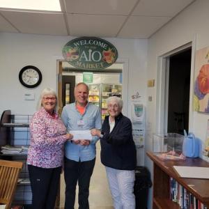 Diane Zollo and Faith Vautour, from Goose River Golf Club's Ladies League, present AIO food pantry CEO Alan Kearl with $1200.