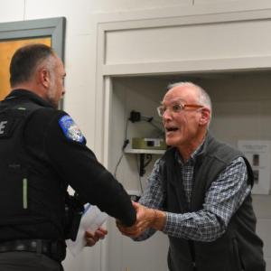 Patrol Officer Chris Hansen shakes hands with Select Board Chair Chris Rector. (Photo by Sarah Thompson)