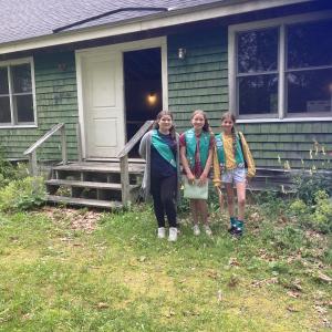 (Photo courtesy Girl Scouts of Maine) Three Girl Scouts stand in front of a house
