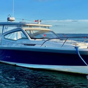 A well-equipped Nimbus W9 buttoned up against the Maine weather with full side curtains and an electrically powered sunroof. The mooring bridle takes advantage of both cleats on the bow. The electric anchor windlass can be operated with a remote control from anywhere on the boat; the remote also can run the bow thruster. The touches of orange are wind vanes on accessory whirligigs meant to deter gulls and cormorants. 