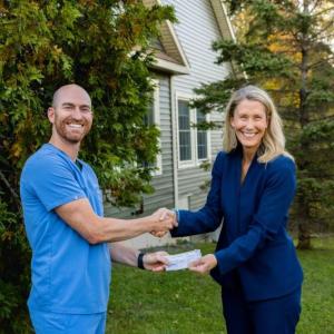 Dentist and community healthcare president pose with check