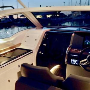 The helm station with its adjustable bucket seats. One large or two smaller computer screens are available, which show course and depth, boat speed, engine RPM, fuel consumption, trim and much, much more. In low visibility, a radar overlay on the chartplotter provides security, backed up by a VHF radio with AIS, Automatic Identification System. The galley, with its refrigerator, propane stove and shelves stocked with Nimbus dishes and flatware, is on the left. The sliding door leads to a comfortable V-berth