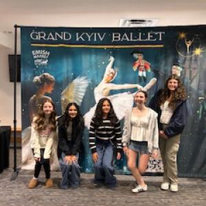 (Photo courtesy Julie Fajardo) Five attendees pose for a picture in front of a large banner of the event