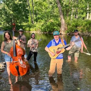 Stillwater band members stand knee-deep in a river
