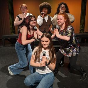 Six girls each hold a microphone