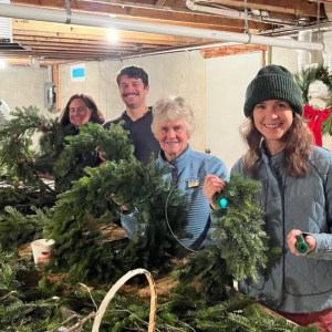 Four people hold up their freshly-made wreaths