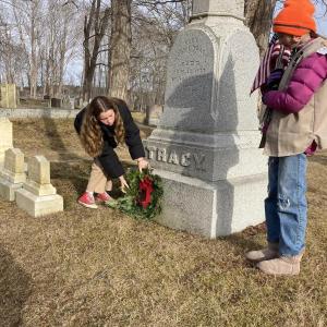 Two females place a wreath