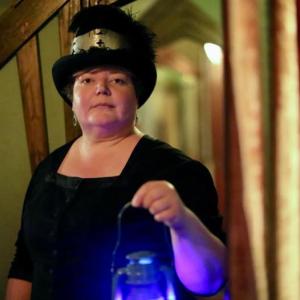 woman in dark clothing holding lantern